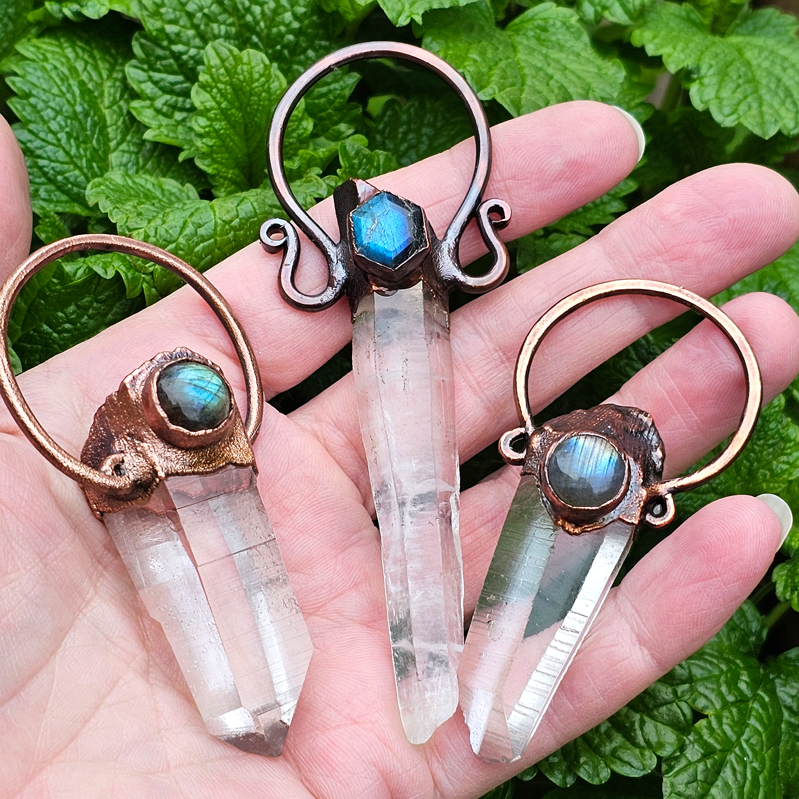 Hand holding three Lumurian Seed Quartz and Copper pendants made by Sparkling Delicious