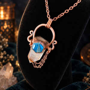 Angled view of a rutilated quartz copper pendant with labradorite and draped chains