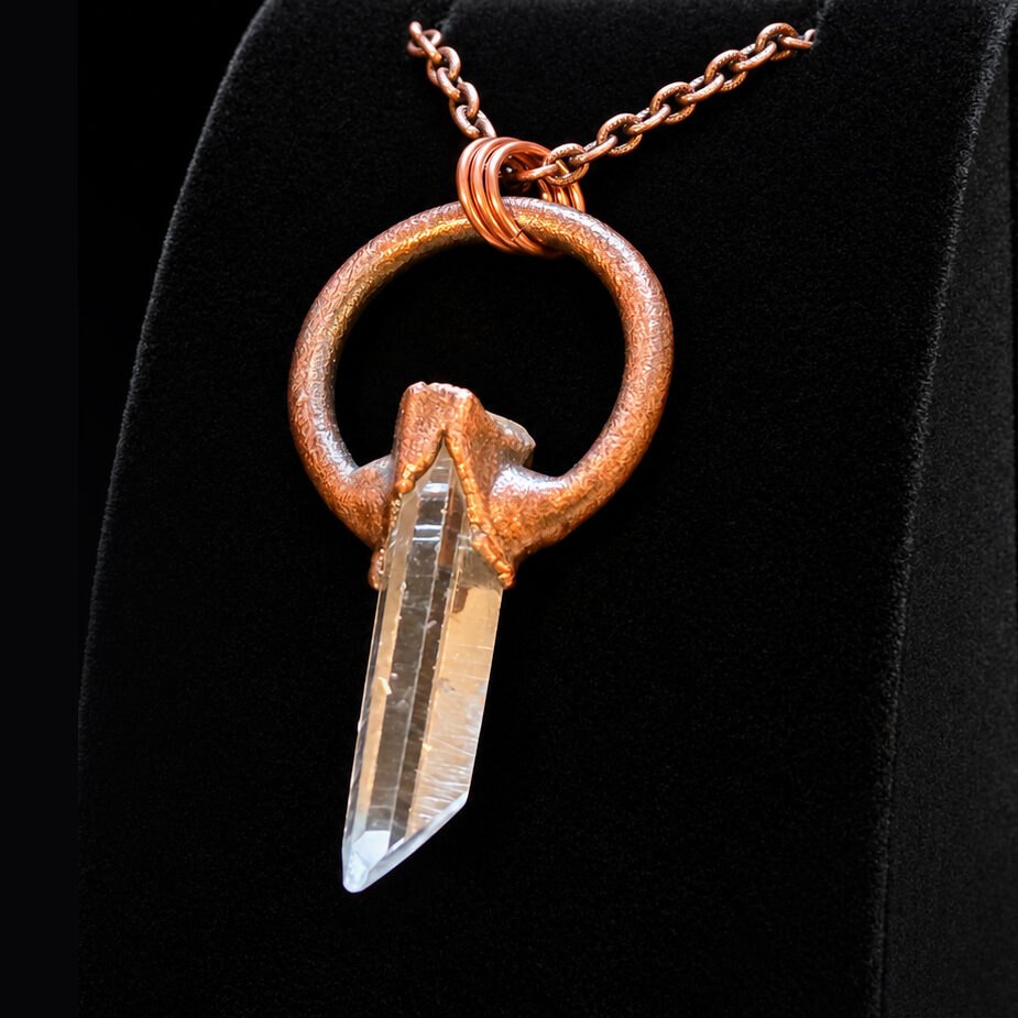 Angled view of a Quartz Crystal Copper Pendant with clear quartz point and copper circle.